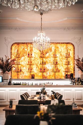 a dining room with a chandelier in front of a wall at Strandhotel Kurhaus Juist in Juist