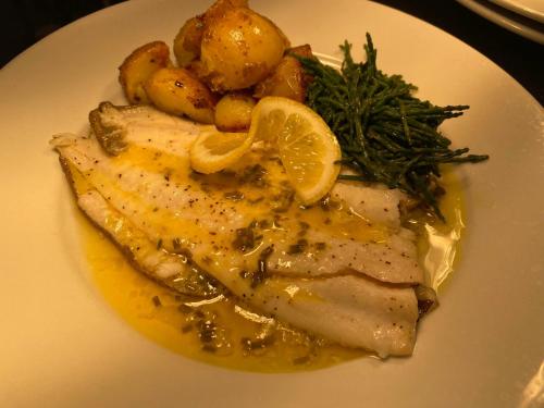 a plate of food with chicken with lemon slices and potatoes at The Griffin Llyswen in Brecon