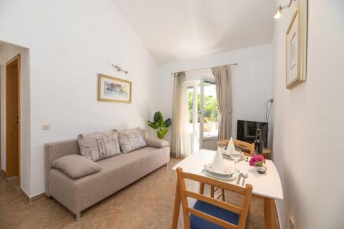 a living room with a couch and a table at APARTMENTS JELENA SUPETAR - three apartments - a small house with a private yard - two-room apartment with a sea view - three-room apartment with garden and barbecue - free parking in Supetar