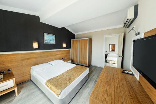 1 dormitorio con 1 cama y TV de pantalla plana en AFYTOS ÖREN PARK MTK, en Burhaniye