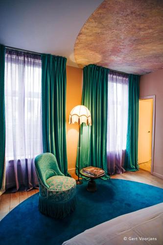 a bedroom with green curtains and a chair and a table at Flora in Antwerp