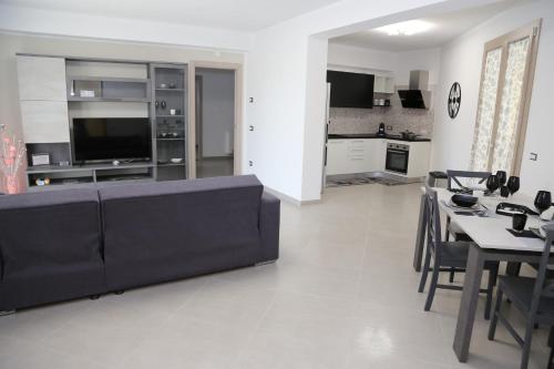 Una sala de estar con un sofá negro y una cocina. en L'OASI DI CICCIO, en Mazara del Vallo