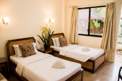 two beds in a room with a window at Marick Beach Resort in Carmen