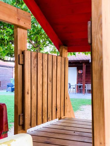 a wooden deck with a red roof on a house at Etzel Tami Hospitality in Neot Golan