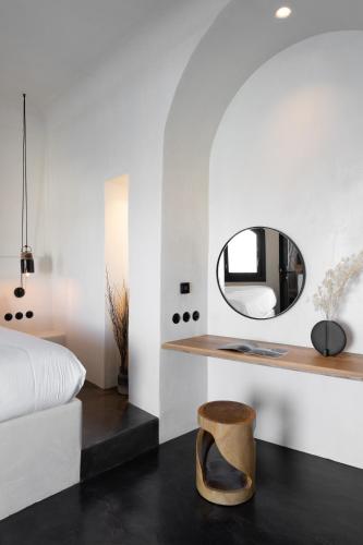 a bedroom with a bed and a mirror and a stool at Stella Rocca A Mare in Imerovigli
