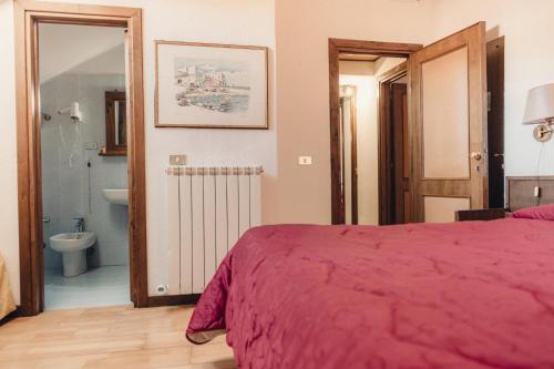 a bedroom with a red bed and a bathroom at Albergo il Plistia in Pescasseroli