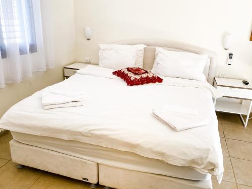 a large white bed with a red scarf on it at Etzel Tami Hospitality in Neot Golan