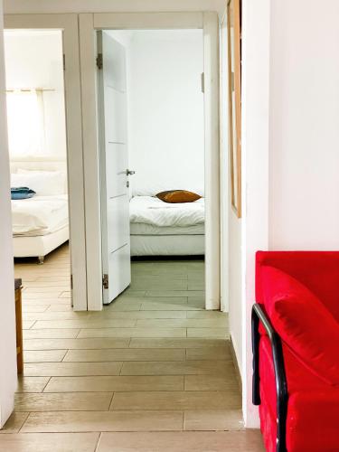 a living room with a red couch and a bedroom at Etzel Tami Hospitality in Neot Golan