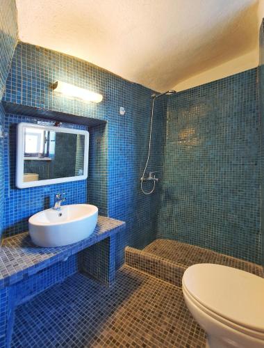 a blue tiled bathroom with a sink and a toilet at Navita Cave Houses in Fira