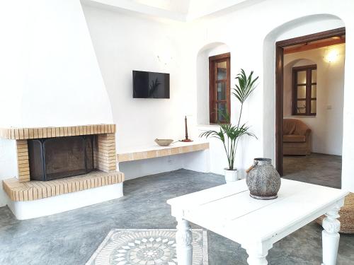 a living room with a table and a fireplace at Navita Cave Houses in Fira