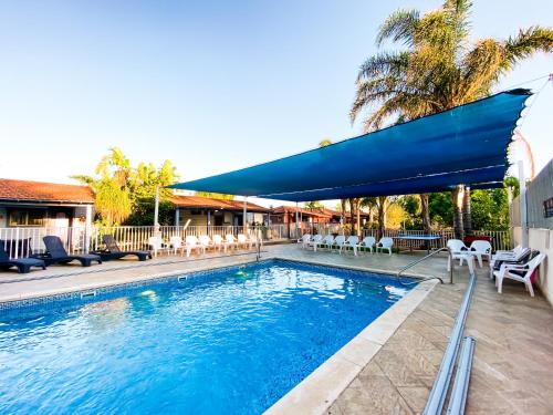 a swimming pool with a blue umbrella and chairs at Etzel Tami Hospitality in Neot Golan