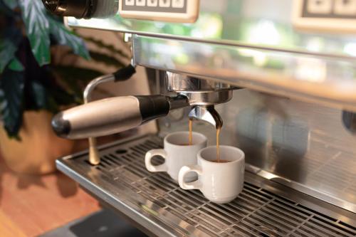 a coffee machine is making two cups of coffee at Résidence Hôtelière les Acanthes in Hossegor
