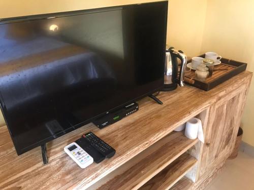 un téléviseur à écran plat posé sur un centre de divertissement en bois dans l'établissement Ubud home stay, à Gianyar