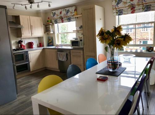 a kitchen with a table with a vase of flowers on it at Norwich City Large Modern Home in Norwich