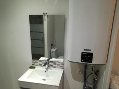 une salle de bain blanche avec un lavabo et un miroir dans l'établissement Alsace N°1, au Mans