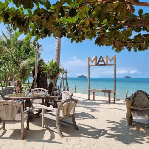 a beach with tables and chairs and a sign that reads man at Mam Kaibae Hotel in Ko Chang