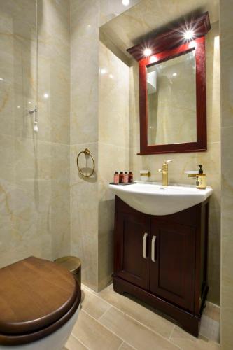 a bathroom with a sink and a toilet and a mirror at History House in Corfu Town