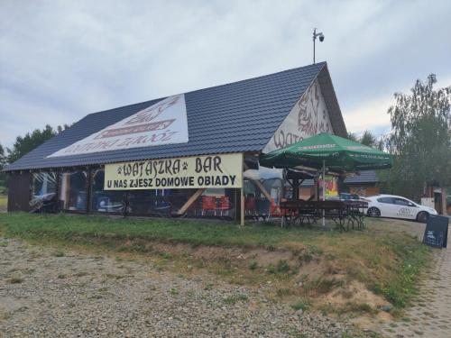 a building with a bar with tables and umbrellas at Wataha Zawóz in Polańczyk