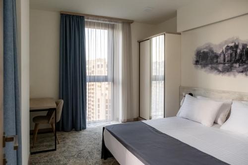 a hotel room with a bed and a desk and window at Rooftop Apart-Hotel in Yerevan