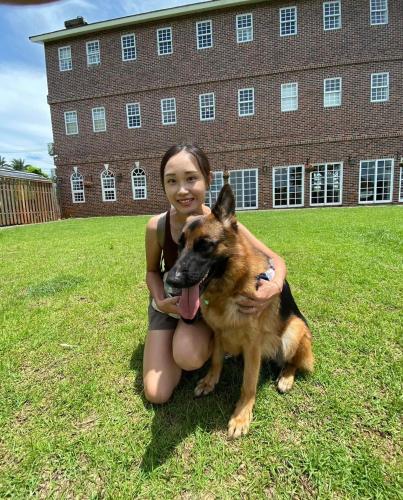 a girl is sitting on the grass with a dog at 墾丁勿忘我城堡莊園 in Hengchun