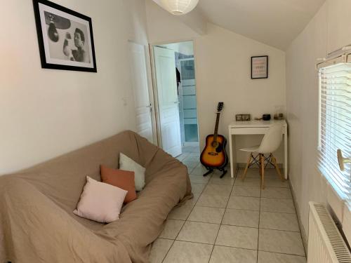 un salon avec un canapé et une guitare dans l'établissement Agréable maison avec parking gratuit sur place., à Saint-Denis