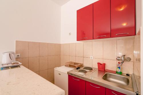 a kitchen with red cabinets and a sink at Apartments Bonaca in Igalo