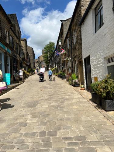 Eine Person, die einen Kinderwagen durch eine Kopfsteinpflasterstraße schubst in der Unterkunft Little Withens in Haworth