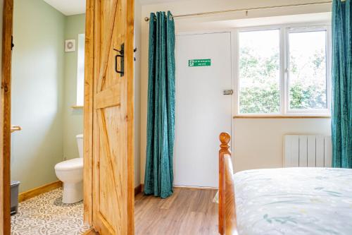 a bedroom with a bed and a window and a toilet at Badgers Drift, Beechcroft Barns, Cawston, Norfolk in Norwich
