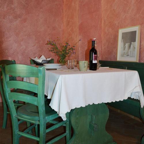 a table with a bottle of wine and a green chair at Agriturismo Monte Gusciani in Massa Marittima