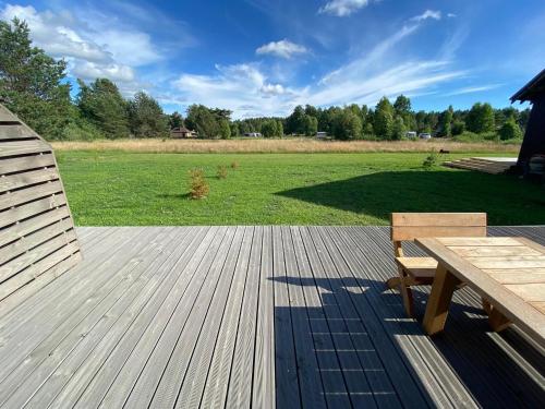una terrazza in legno con tavolo da picnic e campo di Pape Apartament a Pape
