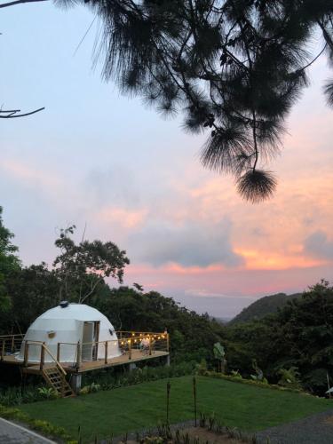 Sorá的住宿－Casa Luna Glamping，山丘上的圆顶帐篷,背景是日落
