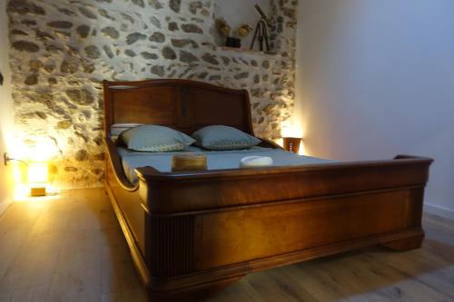 Cama de madera en habitación con pared de piedra en Maison avec Suite Justice Argeles sur Mer en Argelès-sur-Mer