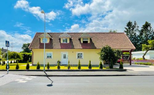 ein gelbes Haus mit rotem Dach auf einer Straße in der Unterkunft Alex's Family Villa in Sjöbo