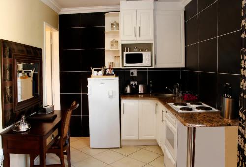 a kitchen with white cabinets and a white refrigerator at Opikopi Guest House in Pretoria