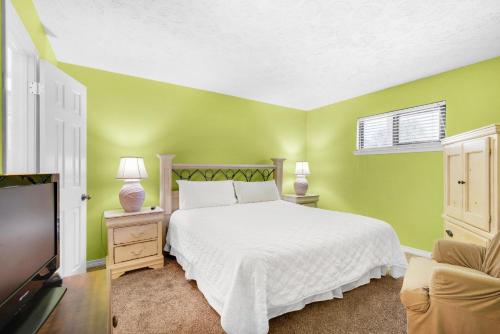 1 dormitorio con cama blanca y paredes verdes en Crystal Villas A-2, en Destin