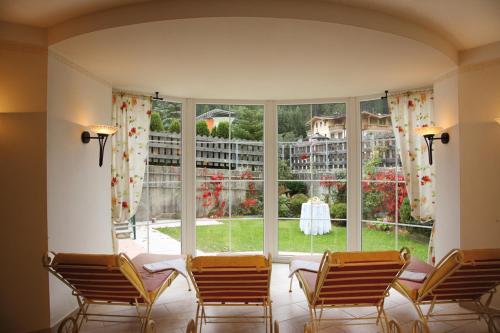 Habitación con 4 sillas y ventana grande. en Hotel Maria Theresia, en Gerlos