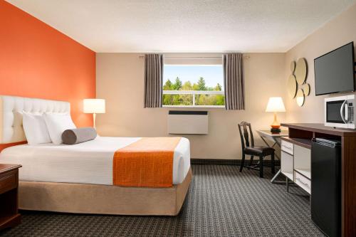 a hotel room with a bed and a desk at Howard Johnson by Wyndham Gravenhurst in Gravenhurst