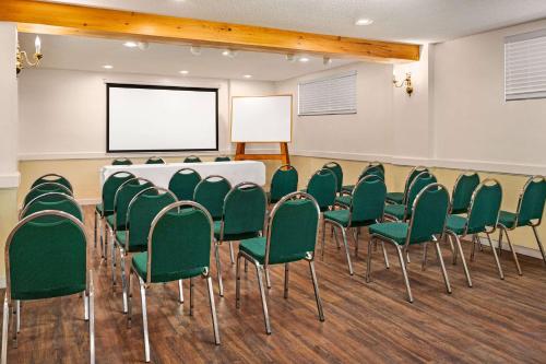 a conference room with a white table and green chairs at Howard Johnson by Wyndham Gravenhurst in Gravenhurst