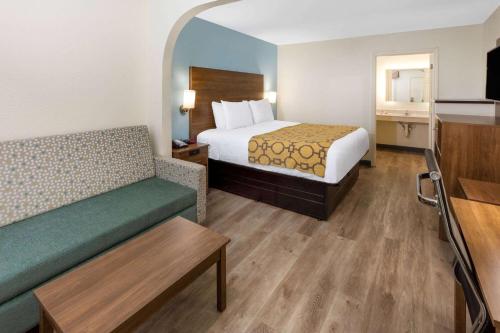 a hotel room with a bed and a couch at Baymont by Wyndham Biloxi - Ocean Springs in Biloxi