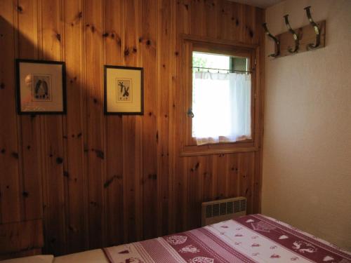 um quarto com uma parede de madeira, uma cama e uma janela em HAMEAU DES HUSKIES em Saint-Gervais-les-Bains