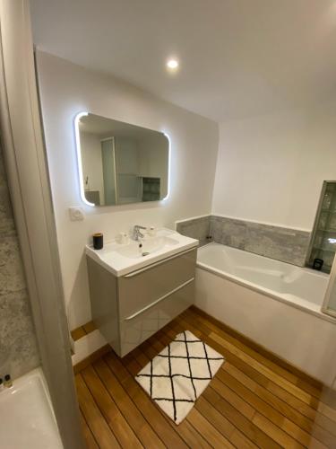 W łazience znajduje się umywalka, wanna i lustro. w obiekcie Cannes Centre ville appartement atypique en duplex 85m2 w Cannes