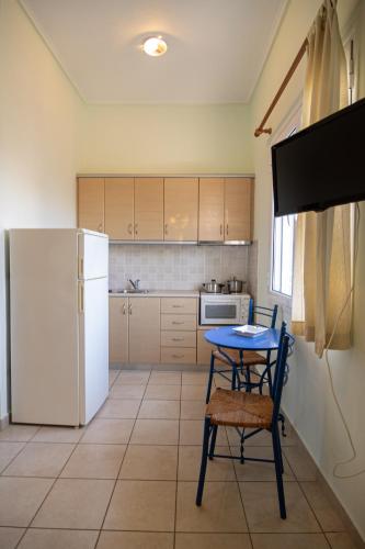 Una cocina con una mesa y un refrigerador blanco. en Tsertos Apartments, en Kamena Vourla