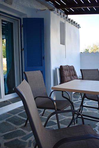 a patio with a table and chairs and a blue door at ΠΑΡΑΔΟΣΙΑΚΗ -ΧΩΡΙΑΤΙΚΗ ΚΑΤΟΙΚΙΑ ΜΕ ΑΥΛΗ in Kithnos