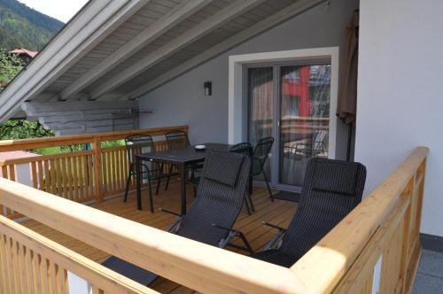 a porch with chairs and a table on a deck at Himmelsbögen und Apartments mit Seeblick und Alleinlage in Weissensee