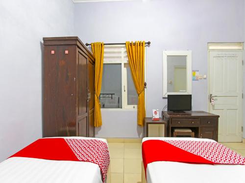 1 dormitorio con 2 camas, tocador y espejo en Super OYO 91315 Homestay Al Maidah, en Sleman