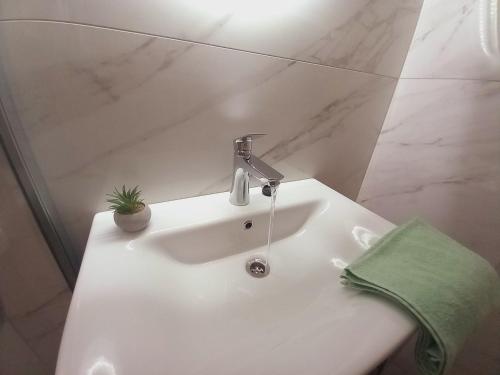 um lavatório branco com uma torneira e uma toalha verde em Apartman La Marija em Prizba