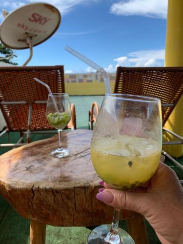 a person holding a glass of wine at a table at Pousada Triplex Pôr Do Sol in Flecheiras