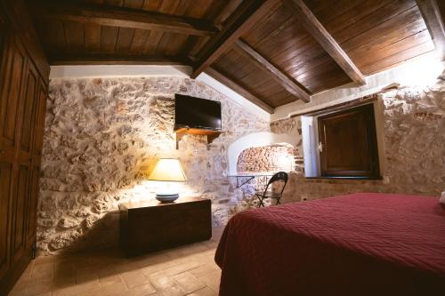sypialnia z czerwonym łóżkiem w kamiennej ścianie w obiekcie Nenà Al Borgo Castello w mieście Pico