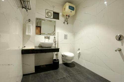 a white bathroom with a sink and a toilet at Airport Hotel Le Seasons New Delhi in New Delhi