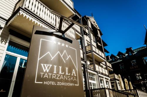 a sign for a hotel in front of a building at Hotel Willa Tatrzańska in Krynica Zdrój